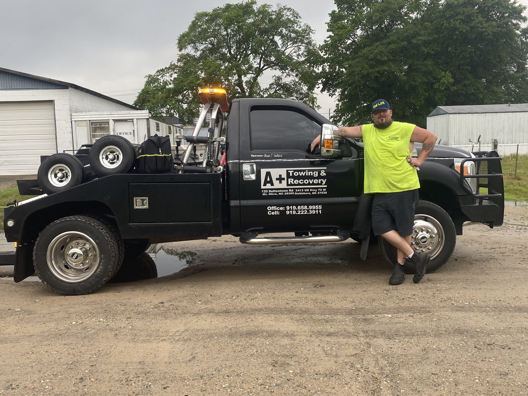 A Plus Towing operator standing beside a recovery truck